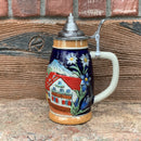 A beautiful presentation of a German Alpine scene with a Chalet and Edelweiss motifs artfully presented around this .75 Liter ceramic beer stein. This beer stein is topped off with an ornate metal lid.